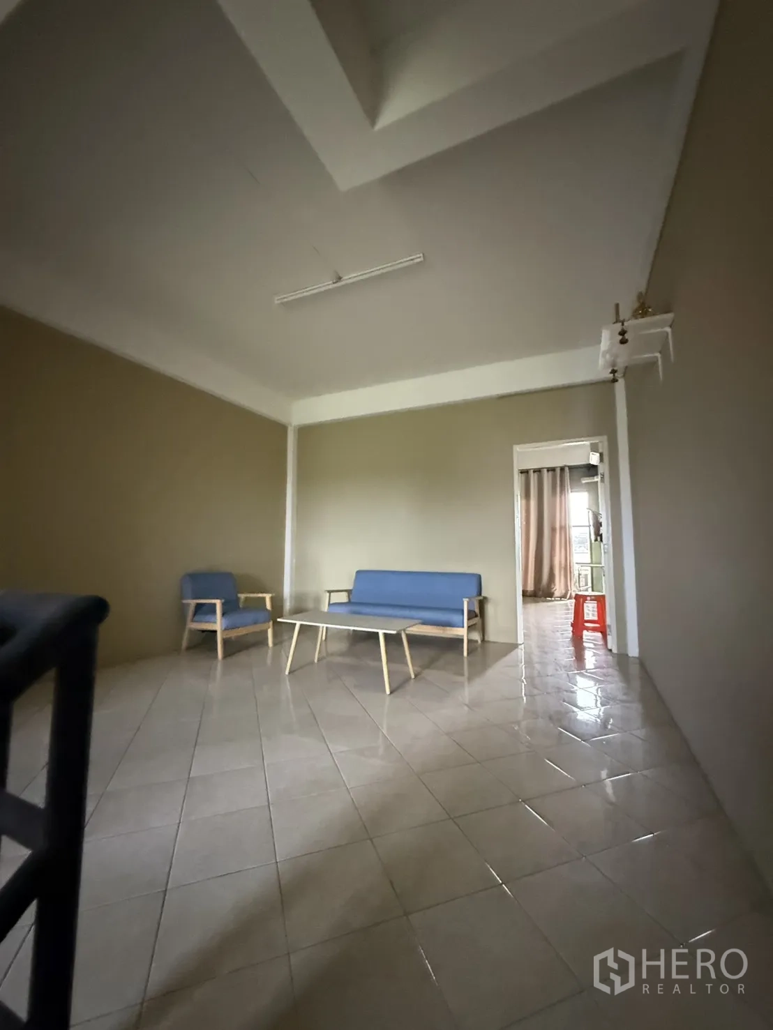 Shophouse for rent in Pak Kret, Nonthaburi - Lounge space with blue armchairs and coffee table on tiled floor.