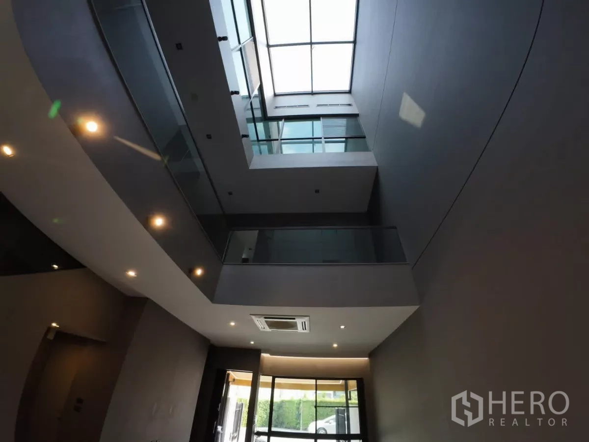Townhouse for rent or sale in Lat Phrao, Bangkok - Double-height atrium with skylight and glass balustrades.