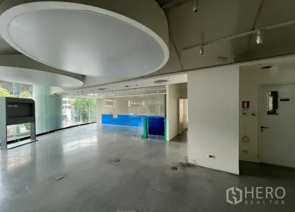 零售空间 出租 - 开间零售内部，通透落地窗、轨道射灯与抛光水泥地面。