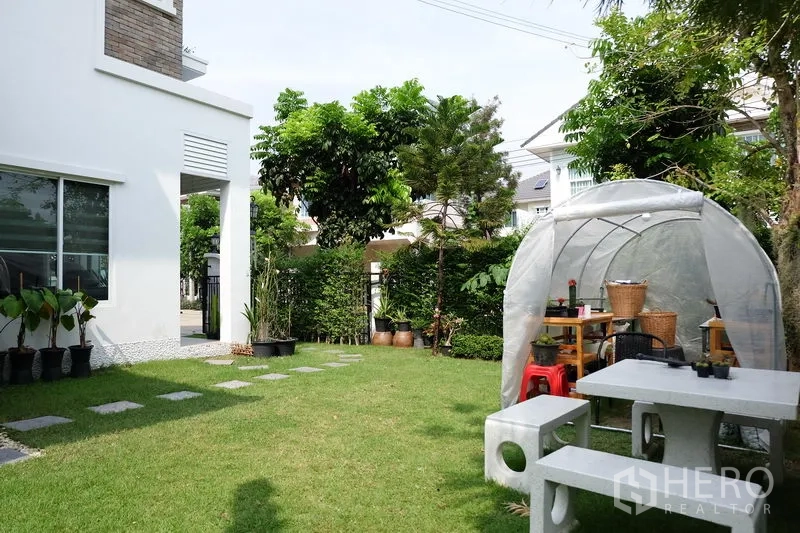 บ้าน ขายในMin Buri, Bangkok - สวนหลังบ้านปูหญ้า ทางเดินแผ่นหิน รั้วพุ่มไม้ และมุมที่นั่งกลางแจ้ง