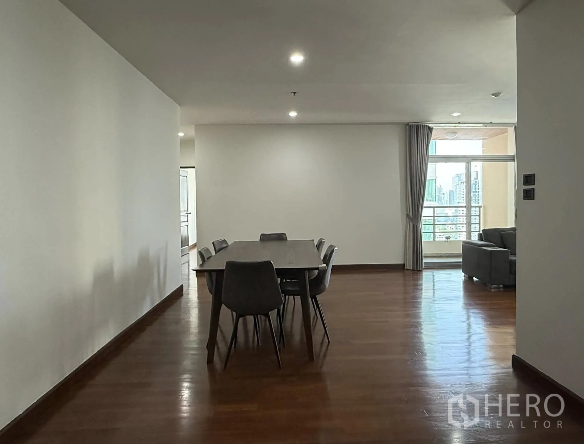 Condominium for rent in Pathum Wan, Bangkok - Open dining area leading toward a balcony and lounge with city outlook.