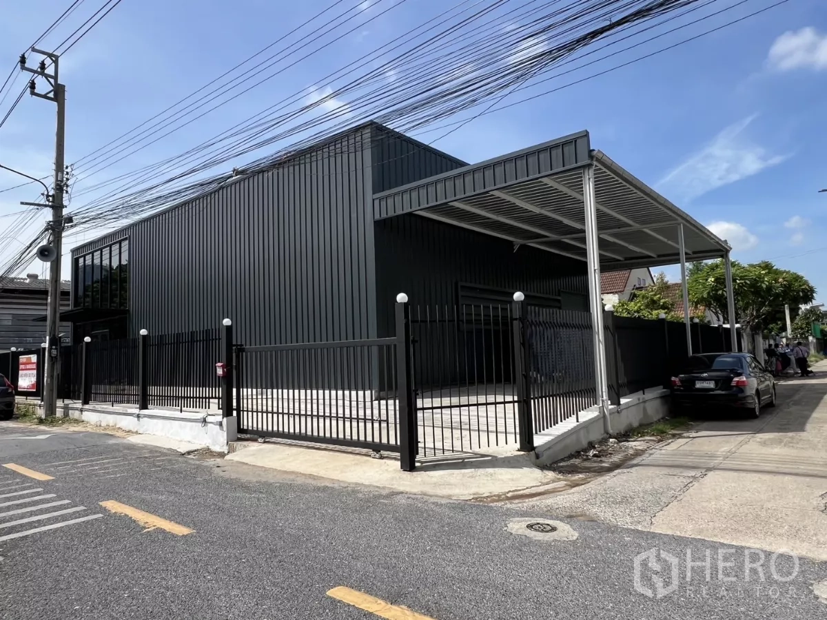 Warehouse for rent in Bang Na, Bangkok - Front elevation of the new warehouse showing sliding gate, canopy, and driveway parking.