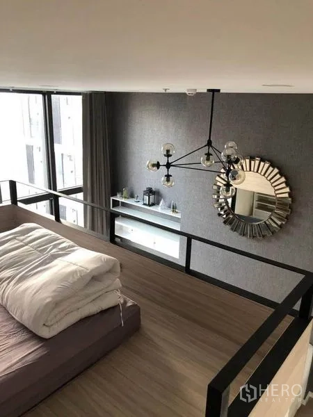 公寓 出售在Ratchathewi, Bangkok - 阁楼卧室俯瞰客厅，吊灯与圆形装饰镜点缀。