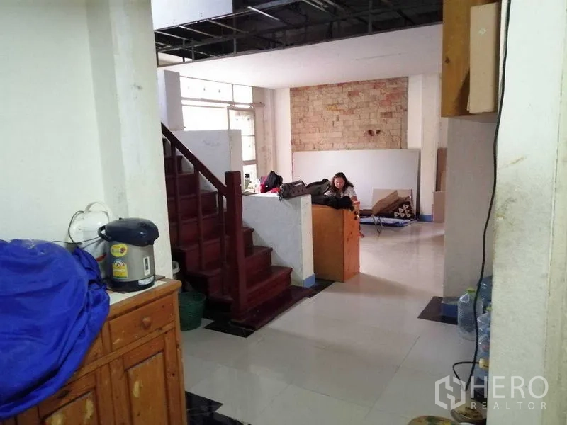 独立式住宅 出售在Prawet, Bangkok - 开放式起居区，红色木楼梯与砖面装饰墙。
