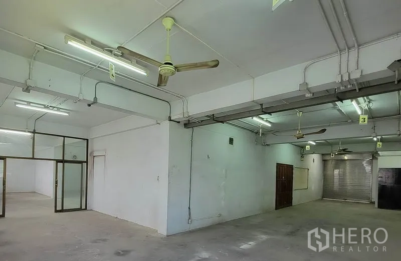 Warehouse for rent in Sam Phran, Nakhon Pathom - Industrial workspace with ceiling fans, exposed conduits and a roller door.