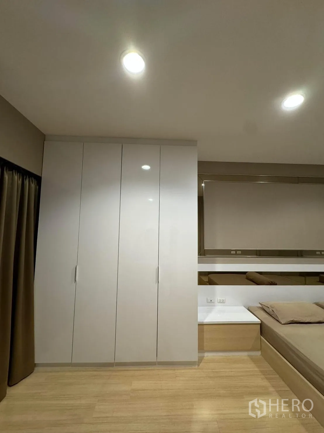Townhouse for rent in Suan Luang, Bangkok - Bedroom with built-in wardrobe, bedside table and warm wood floors.