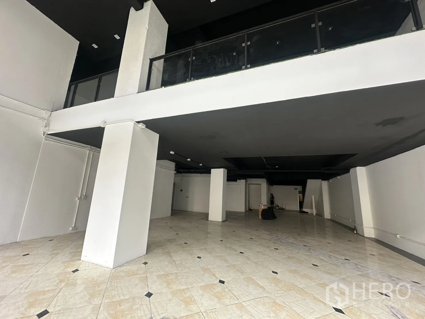 Retail Space for rent in Pathum Wan, Bangkok - Spacious ground floor with tiled flooring, white columns, and a mezzanine.