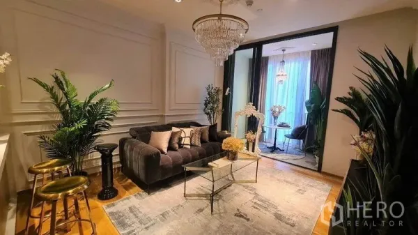 Condominium for rent in Khlong Toei, Bangkok - Elegant living room with crystal chandelier, velvet sofa, glass coffee table and indoor plants.