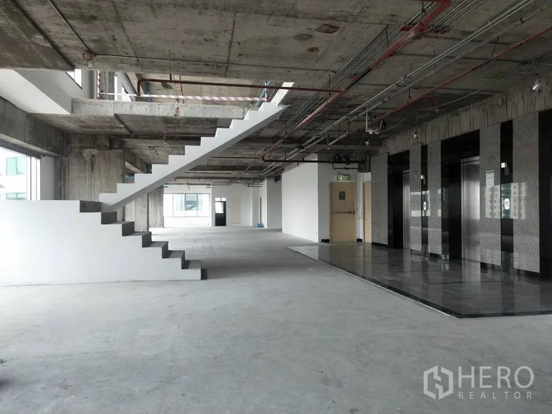 办公空间 出租在Watthana, Bangkok - 办公室电梯厅与内部楼梯，混凝土天花与毛坯地面。