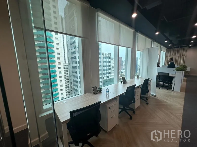 Office Space for rent - Row of window-facing desks with roller blinds and Bangkok city views.