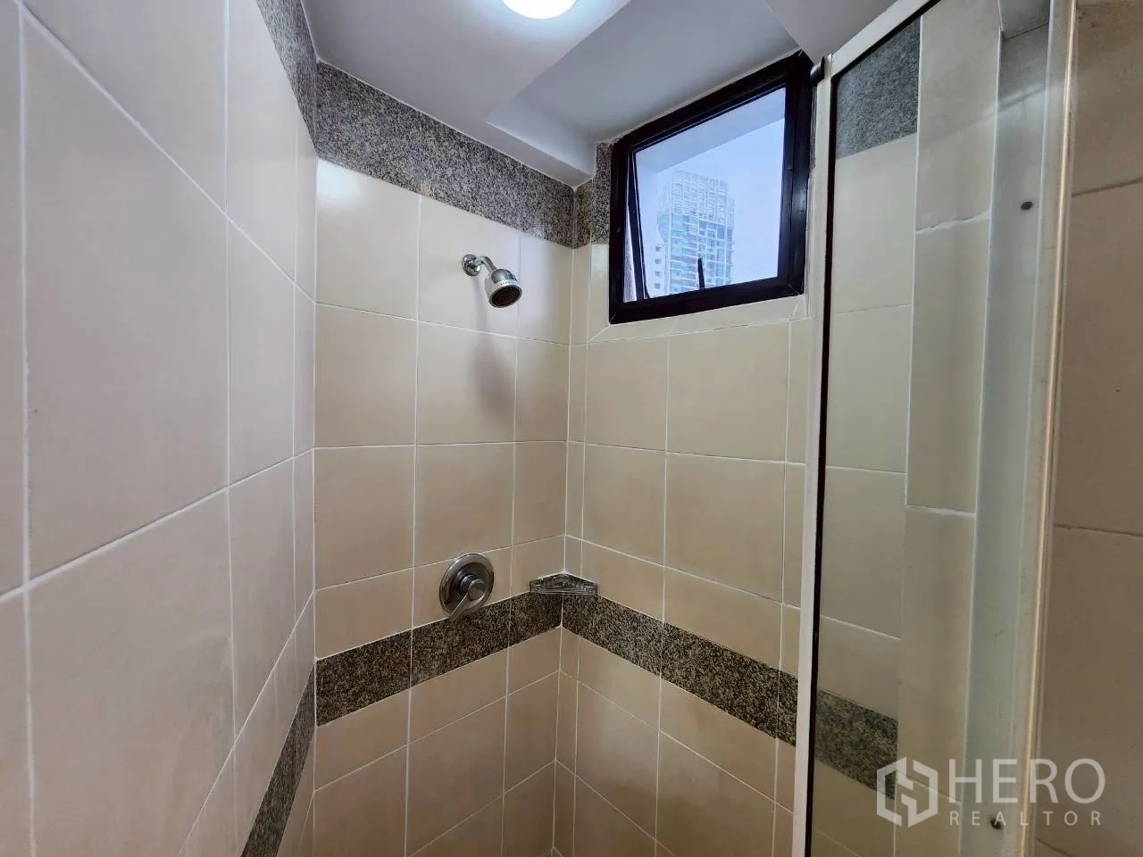 Condominium for rent in Khlong Toei, Bangkok - Tiled shower stall with window and chrome fixtures.