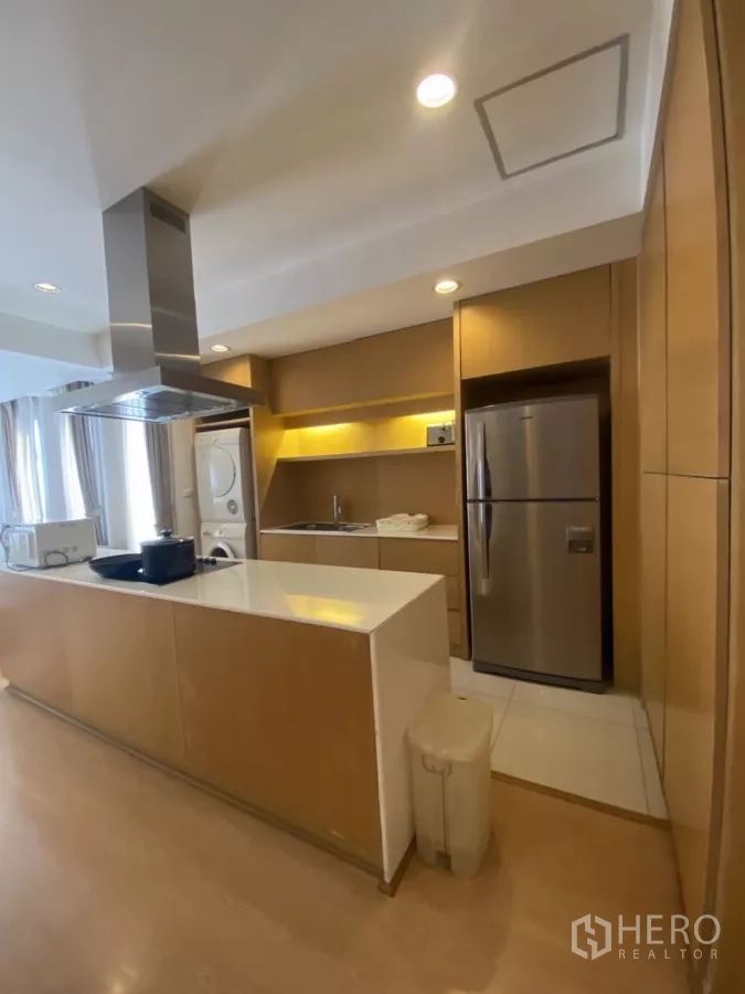 Condominium for rent in Watthana, Bangkok - Fitted kitchen with under-cabinet lighting, stacked washer-dryer and large stainless refrigerator.