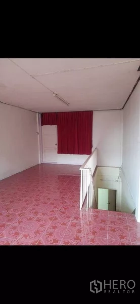 Shophouse for rent or sale in Phra Khanong, Bangkok - Spacious tiled room on the upper floor with red curtain and open stairwell.