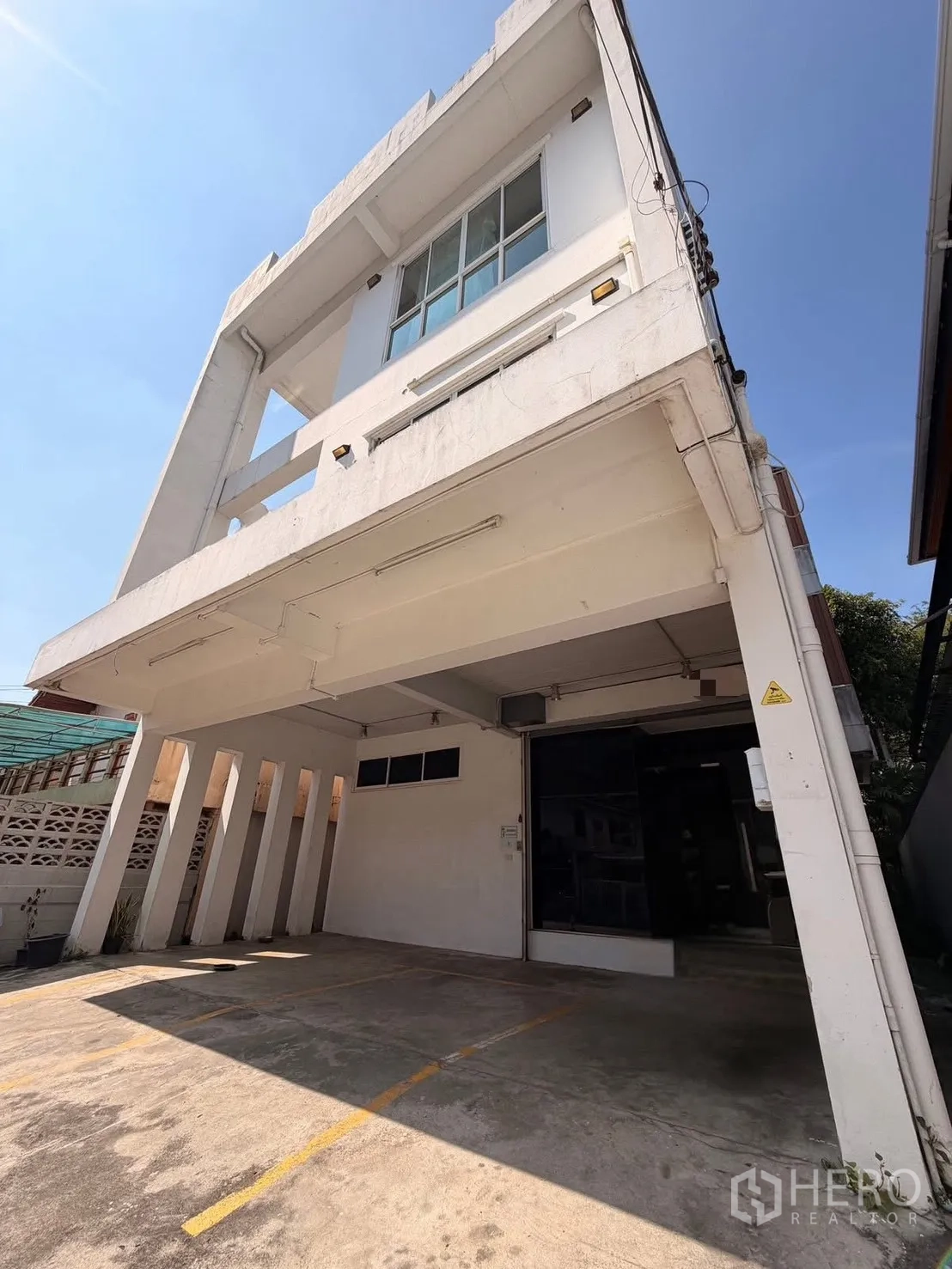 带办公室的家 for rent in Huai Khwang, Bangkok - 现代白色立面下的有顶停车区。