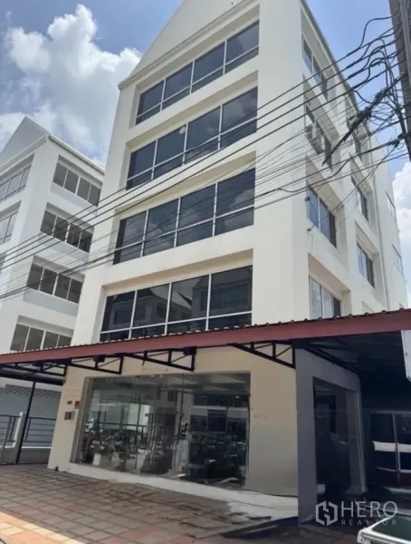 办公空间 出租在Bueng Kum, Bangkok - 六层白色办公楼，整面玻璃窗与一层展示大厅。