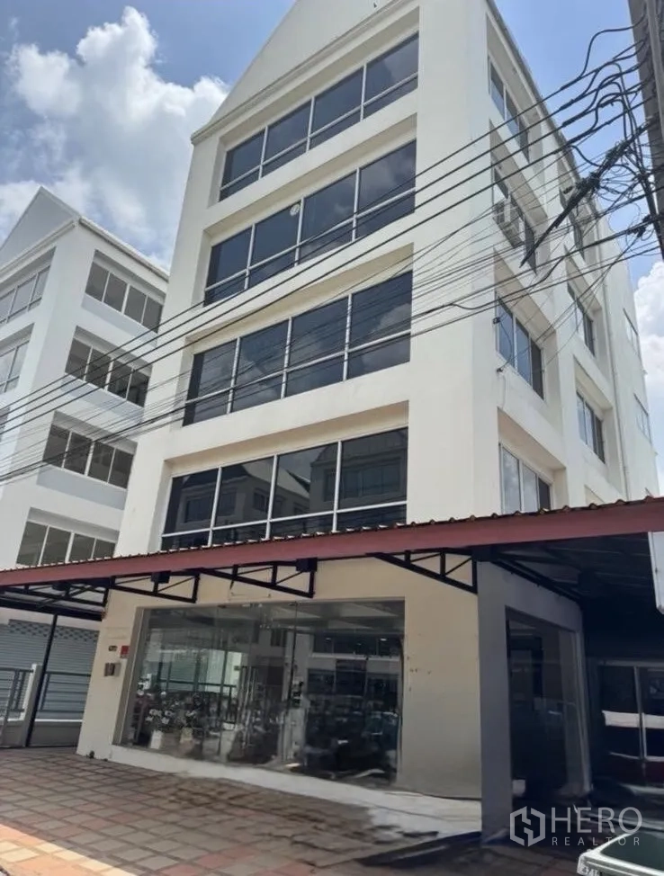 办公空间 出租在Bueng Kum, Bangkok - 六层白色办公楼，整面玻璃窗与一层展示大厅。