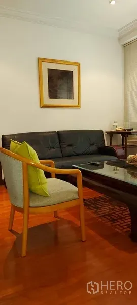 Condominium for rent in Sathon, Bangkok - Side view of the lounge showing a framed artwork, sofa, accent chair and recessed lighting.