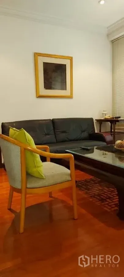 Condominium for rent in Sathon, Bangkok - Side view of the lounge showing a framed artwork, sofa, accent chair and recessed lighting.