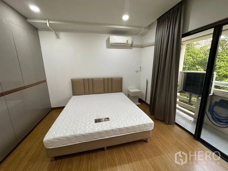 Condominium for rent in Watthana, Bangkok - Bedroom with balcony access, built-in wardrobe and wood floors.