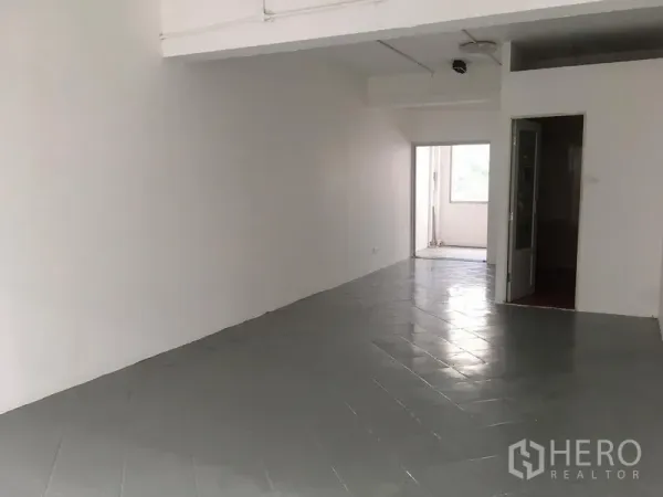 店屋 出租在Khlong Toei, Bangkok - 楼层空间铺灰色瓷砖，白墙，并有门通向小阳台区域。