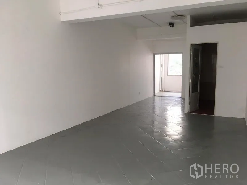 店屋 出租在Khlong Toei, Bangkok - 楼层空间铺灰色瓷砖，白墙，并有门通向小阳台区域。