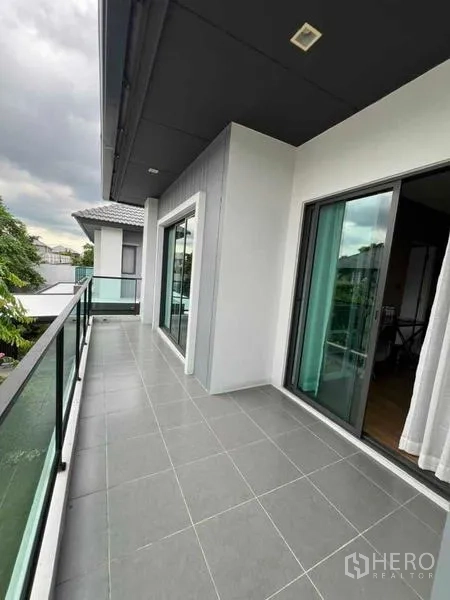 Detached House for sale in Khan Na Yao, Bangkok - Wide second-floor balcony with tiled floor and clear glass railing.