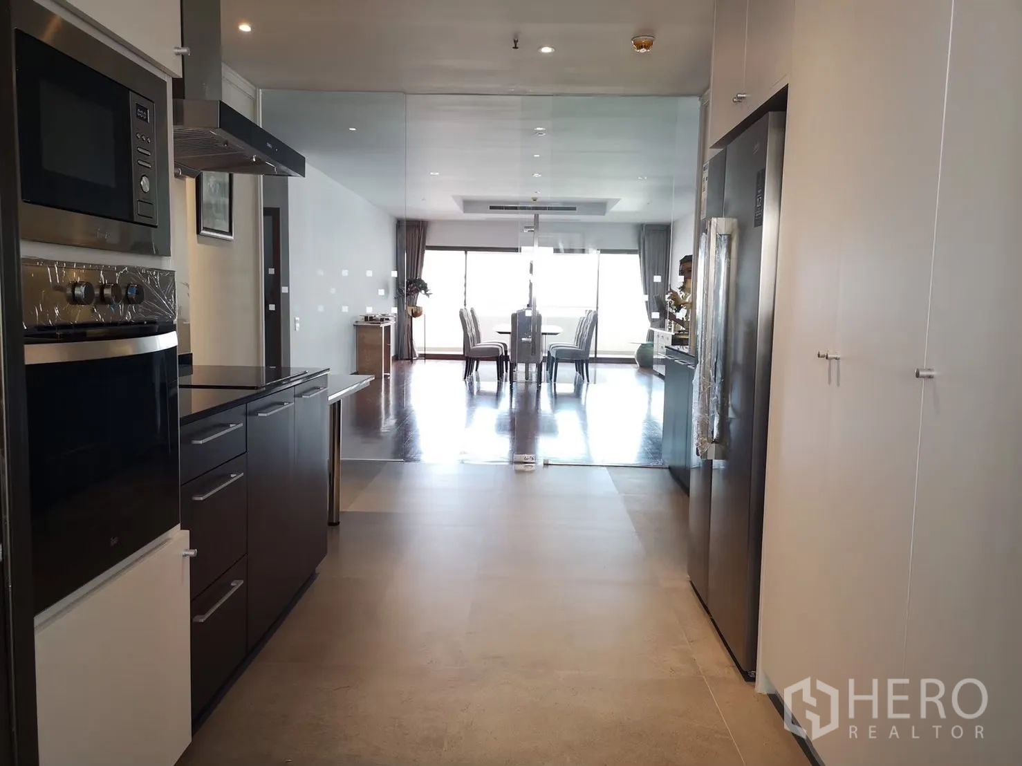 Condominium for rent in Bangkok - Long galley kitchen with built-in oven and large fridge opening to the dining room.
