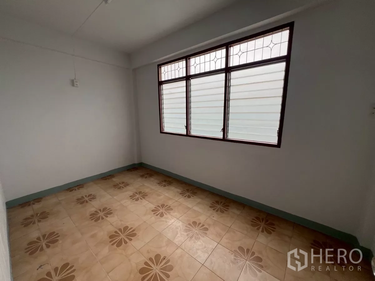 Shophouse for rent in Khlong Toei, Bangkok - Secondary room with patterned tiles and grilled window allowing daylight.
