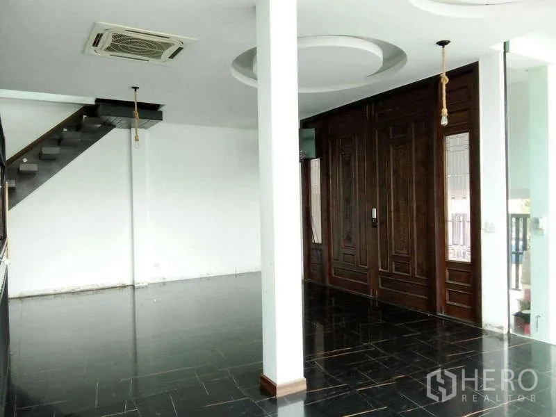 独立式住宅 出售在Lat Phrao, Bangkok - 一层大厅黑色地砖，双开木门与悬浮楼梯。
