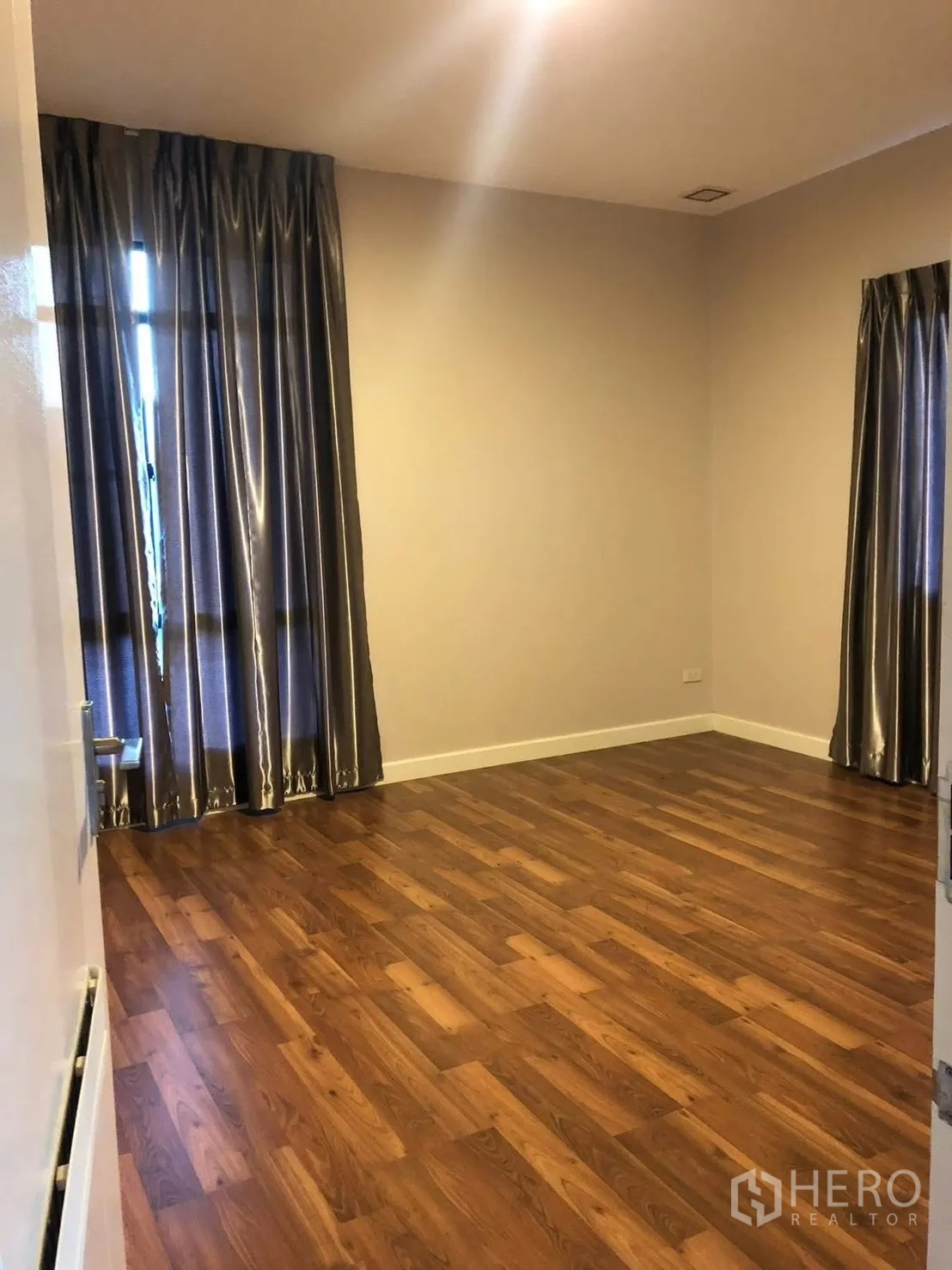 Detached House for rent in Prawet, Bangkok - Spacious bedroom with wooden floor and full-length curtains.