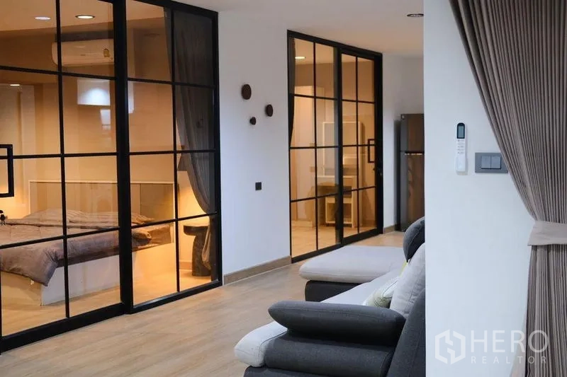 Condominium for rent in Bang Rak, Bangkok - Open corridor with black-framed glass partitions connecting bedrooms and lounge.