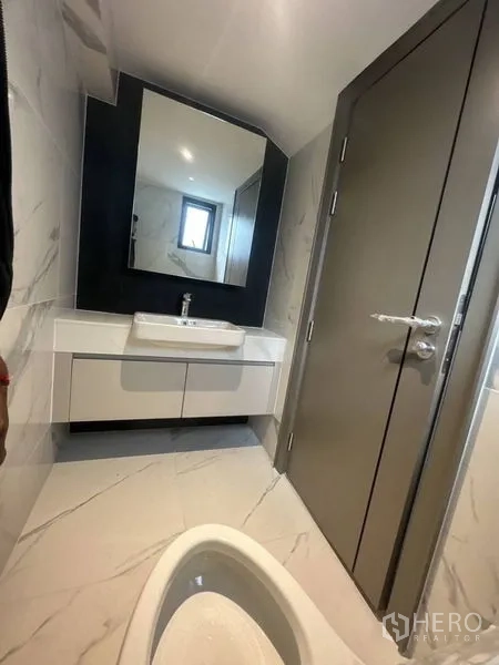 Detached House for rent - Compact guest bathroom with wall-mounted sink, large mirror and marble-effect tiles.