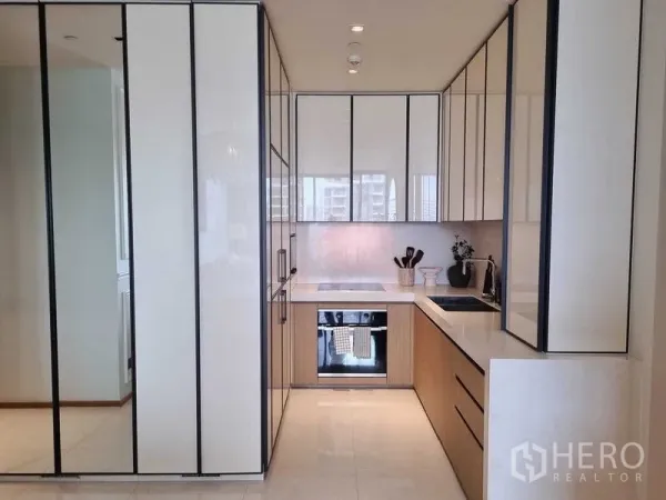 Condominium for sale - Sleek U-shaped kitchen with glossy cabinets, built-in oven and cooktop.