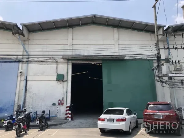 Warehouse for rent in Khlong Luang, Pathum Thani - Warehouse facade with large green shutter and parking area in Khlong Luang, Pathum Thani.