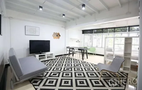 Home Office for rent in Khlong Toei, Bangkok - Spacious living area with sofa, TV, dining table, and large windows over a monochrome rug.