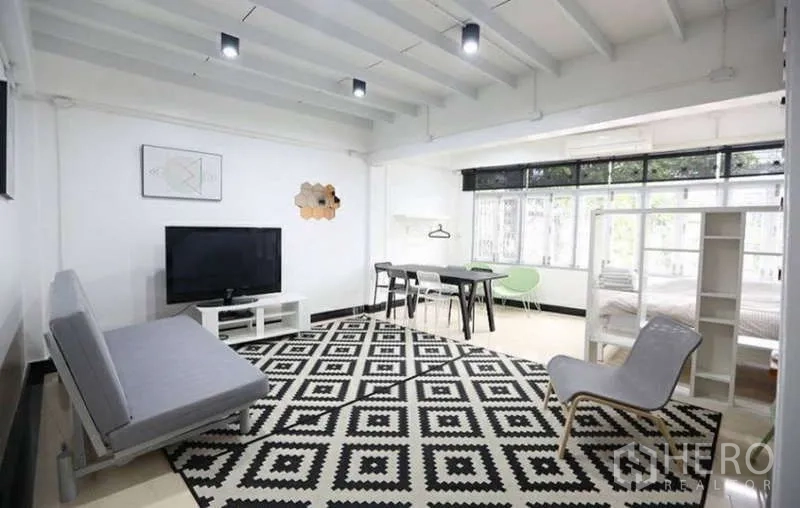 Home Office for rent in Khlong Toei, Bangkok - Spacious living area with sofa, TV, dining table, and large windows over a monochrome rug.