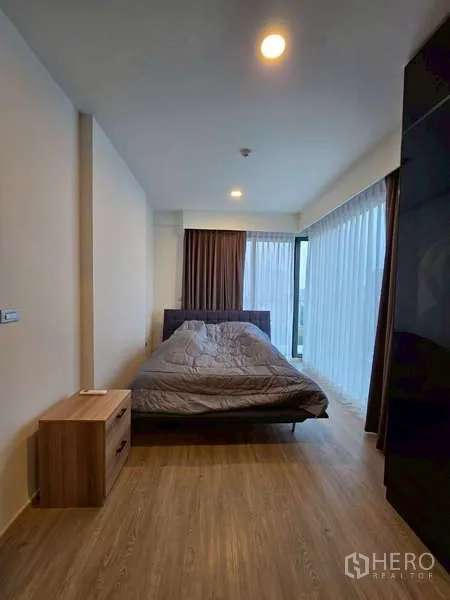公寓 出租在Phaya Thai, Bangkok - 主卧转角落地窗，纱帘与木纹地板。