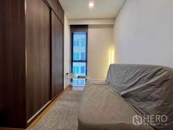Condominium for rent - Compact multipurpose room with dark wood wardrobe, sofa bed and floor-to-ceiling window.