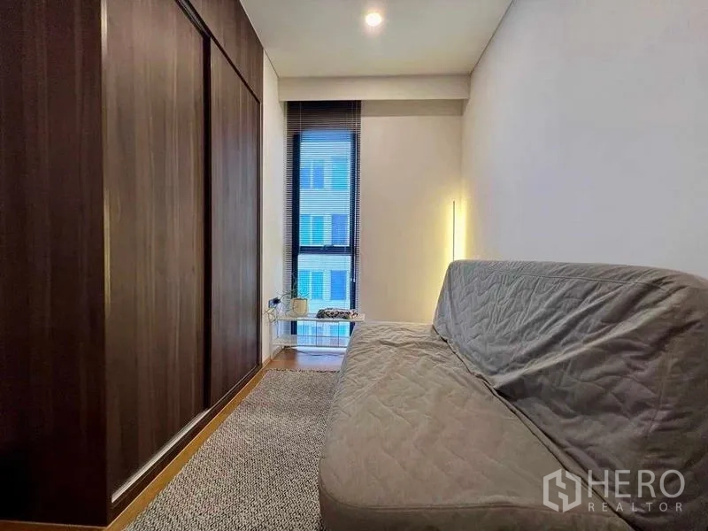 Condominium for rent - Compact multipurpose room with dark wood wardrobe, sofa bed and floor-to-ceiling window.