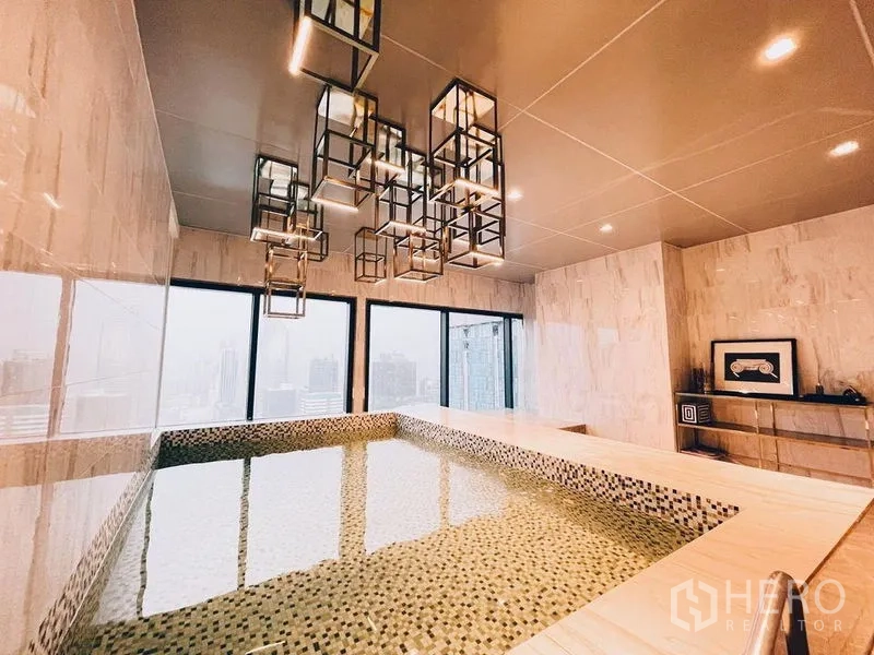 Condominium for rent in Ratchathewi, Bangkok - Indoor onsen‑style soaking pool with pendant lights and city panorama.