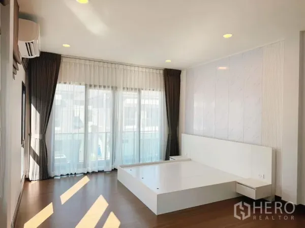 บ้าน ให้เช่าในBang Phli, Samut Prakan - ห้องนอนใหญ่ ฐานเตียงบิวท์อิน ม่านโปร่ง และประตูกระจกออกระเบียง