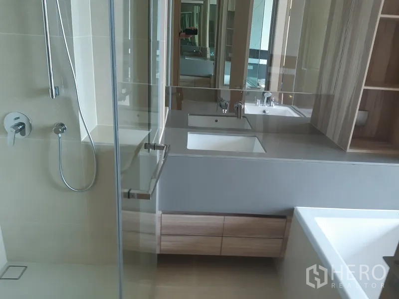 Condominium for rent or sale in Watthana, Bangkok - Modern bathroom with floating vanity, glass shower and built-in shelving.