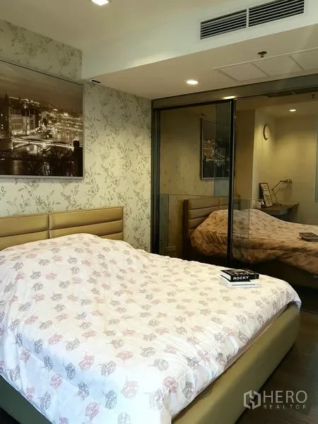 Condominium for rent in Sathon, Bangkok - Master bedroom showing glass partition and wallpapered feature wall.