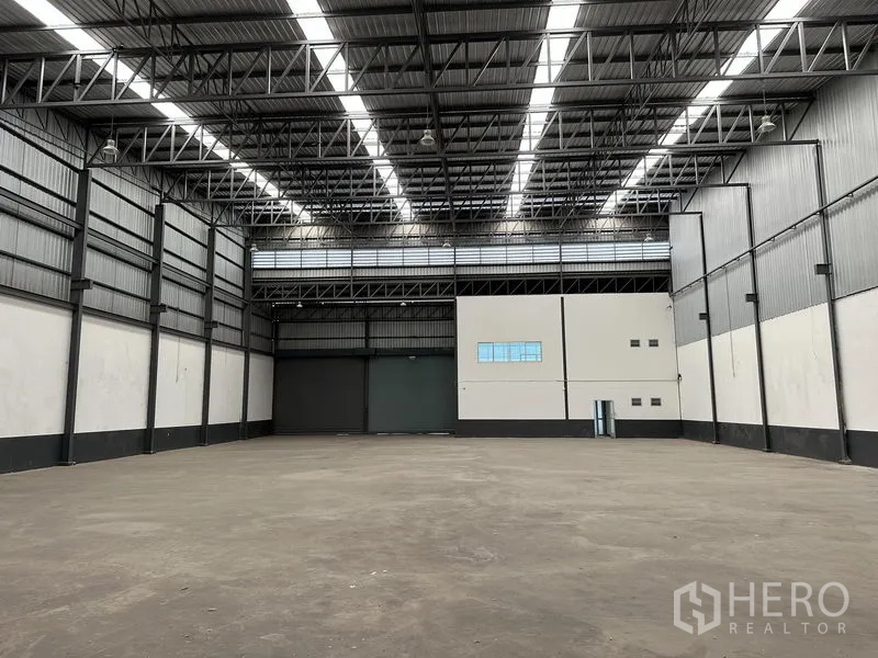 Warehouse for rent in Samut Prakan - Warehouse interior facing large loading doors and a mezzanine-style office block.