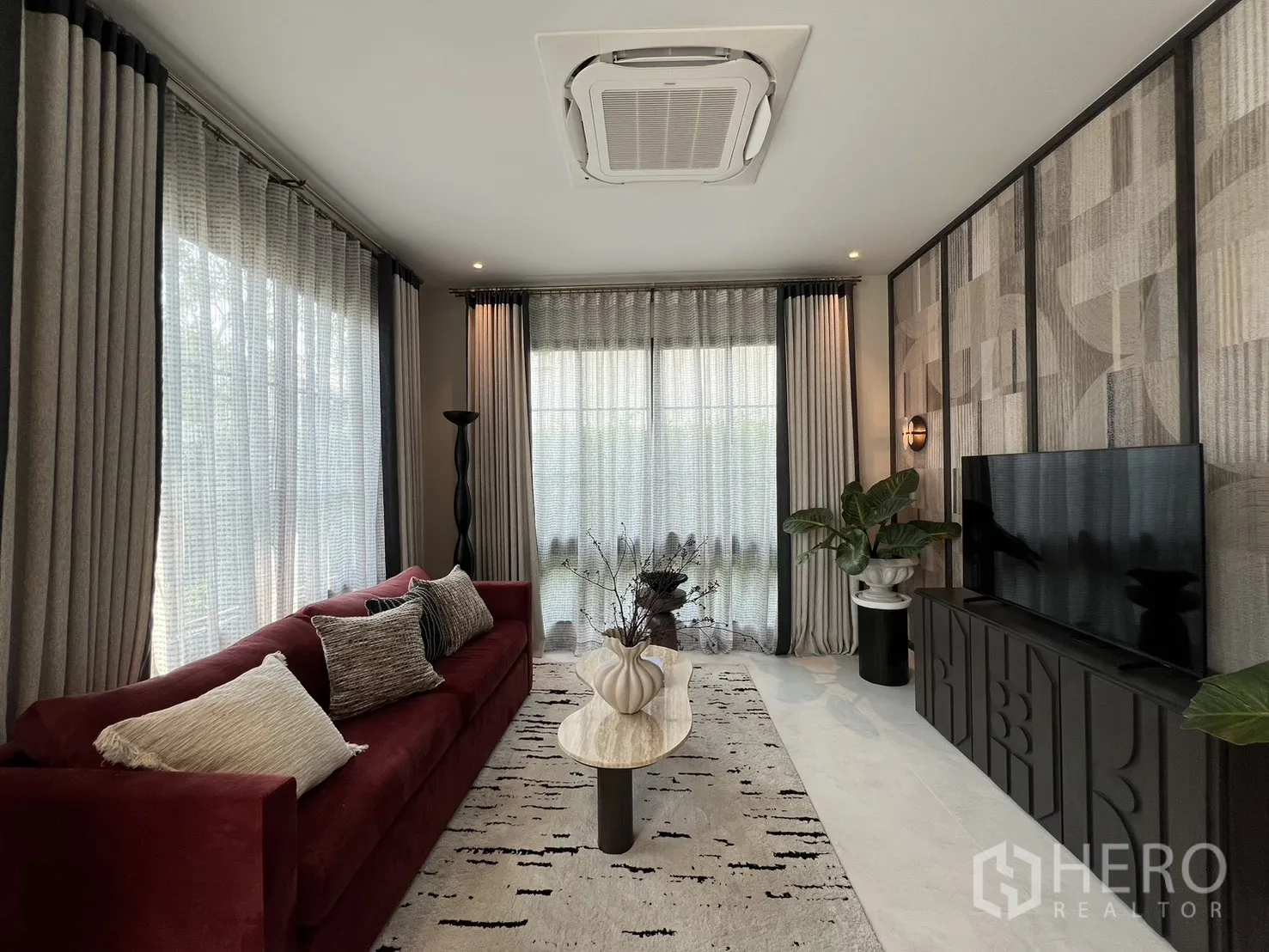 独栋房屋 for rent in Bang Phli, Samut Prakan - 客厅配红色沙发、电视柜、几何墙面与吊顶空调。