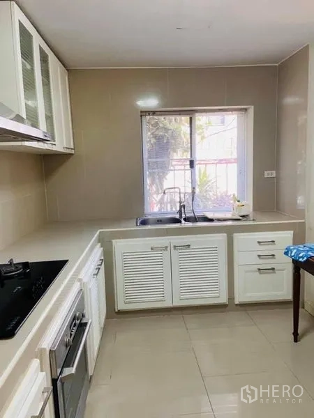 Detached House for rent in Watthana, Bangkok - Fitted kitchen with white cabinetry, gas hob, oven and a window for natural light.