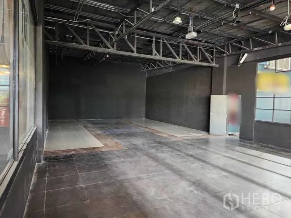Retail Space for rent in Khlong Toei, Bangkok - Open-plan unit featuring steel trusses, a windowed wall and a service door, suitable for multiple uses.