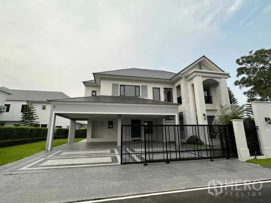 独立式住宅 出售在Lat Krabang, Bangkok - 正立面视角的当代独栋别墅，黑色金属大门与大面积有顶停车区。