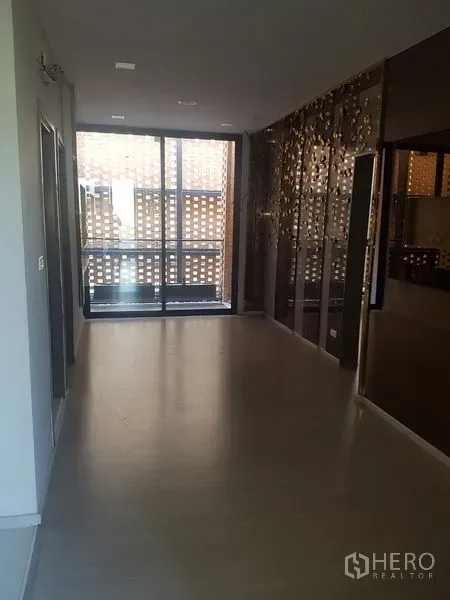 Retail Space for rent in Khlong Toei, Bangkok - Open-plan showroom area with dark mirrored feature wall and sliding glass doors behind a brick screen.
