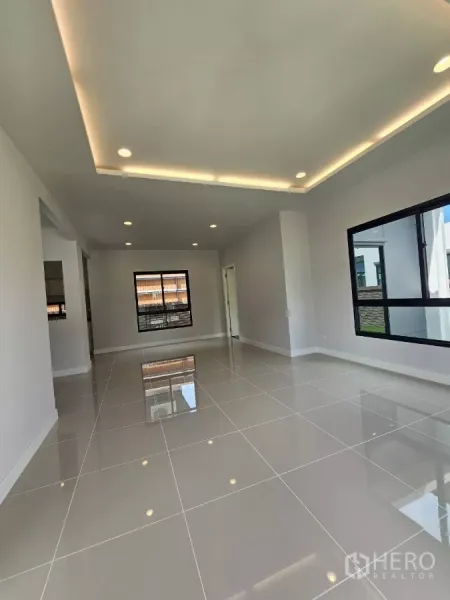Detached House for sale in Lam Luk Ka, Pathum Thani - Bright open-plan living room with recessed lighting and glossy tiled floors.